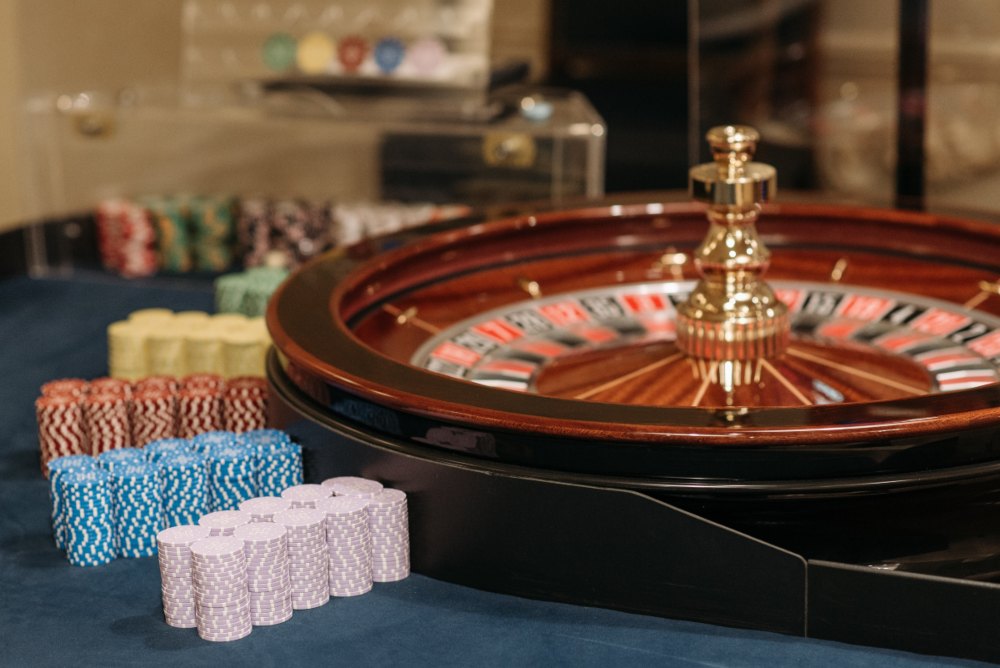 pexels-pavel-danilyuk-7594182 (1) Roulette wheel with casino chips stacked on roulette table.